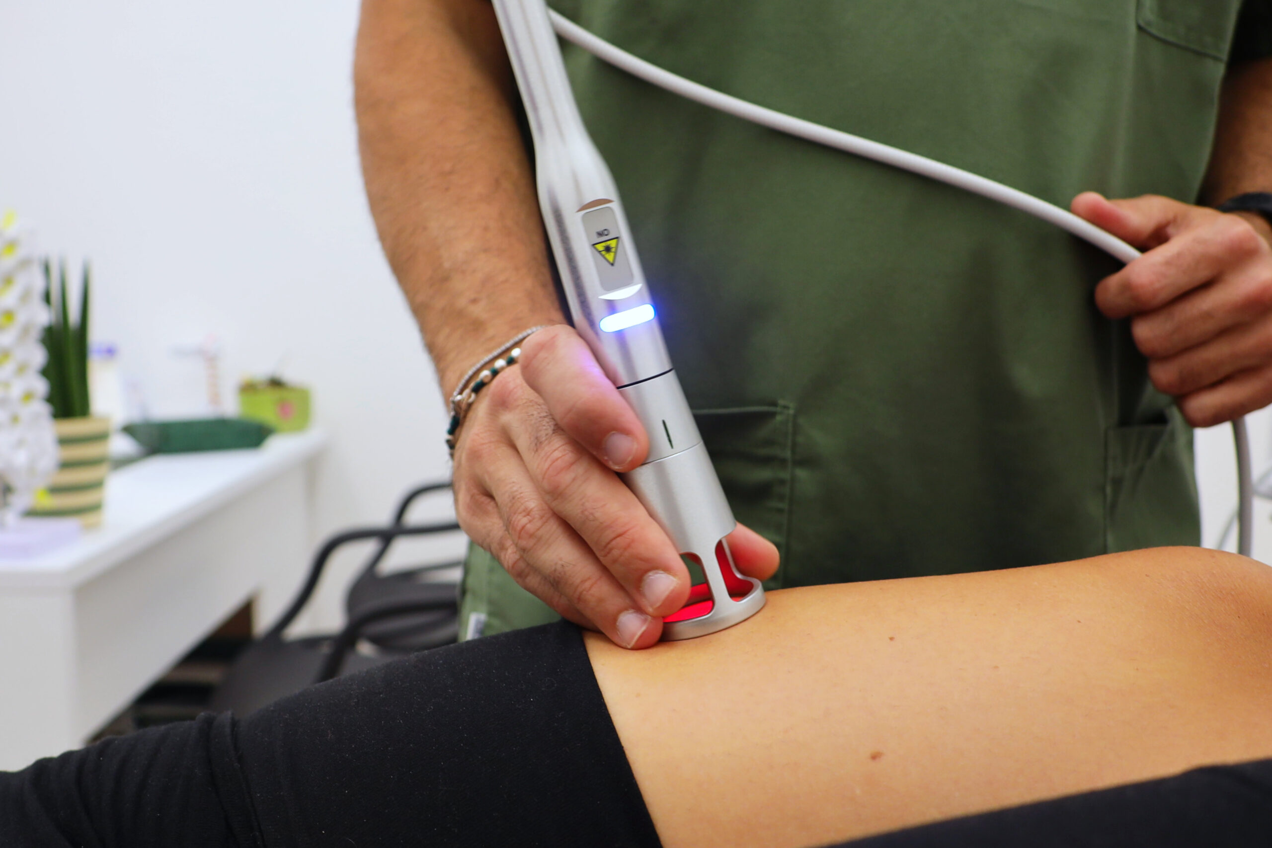 Fisioterapista applica un dispositivo laser terapeutico sul braccio di una paziente